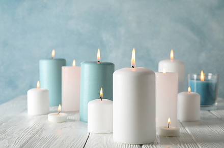Different burning candles against blue background, space for tex