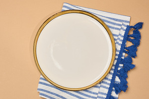 Empty white plate with a gold rim on a striped blue and white na, a Food & Drink Photo by ndanko
