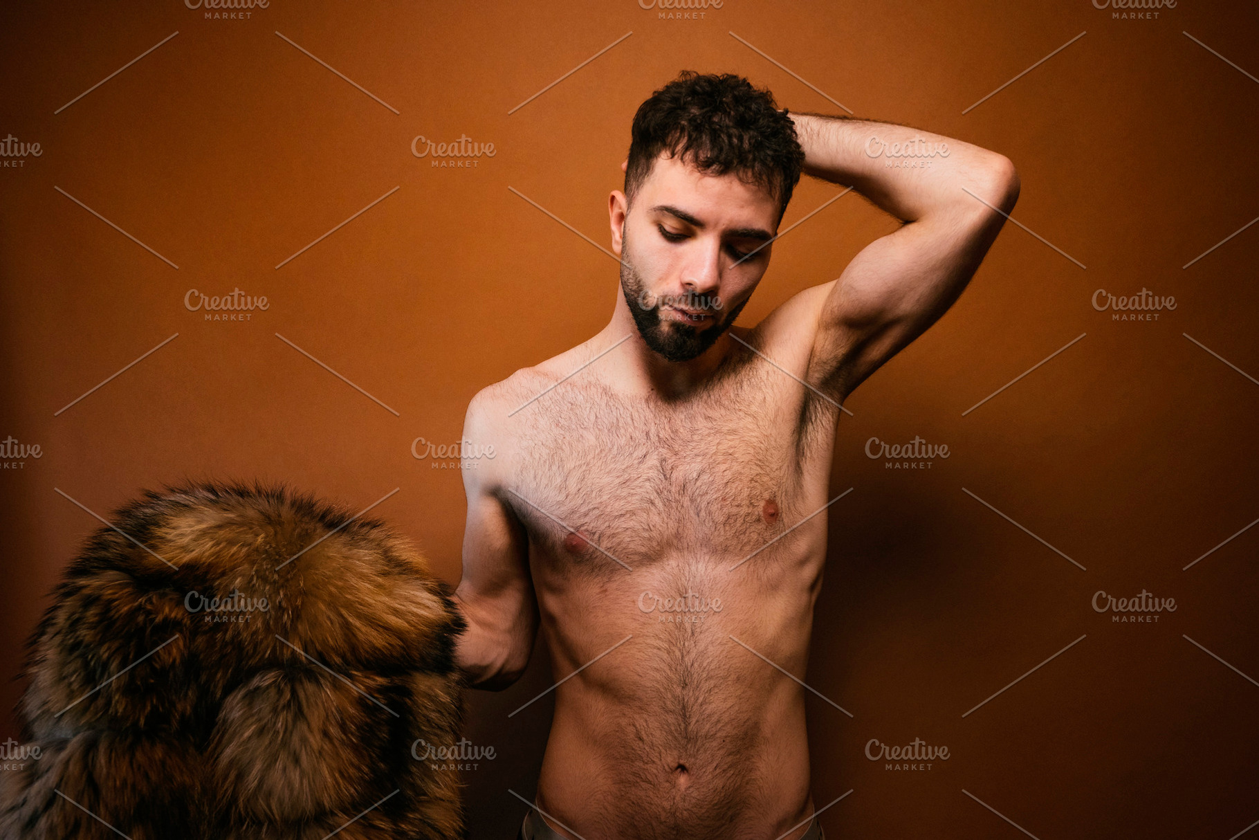 Bearded man posing shirtless with fur coat, a Photo by karrastock