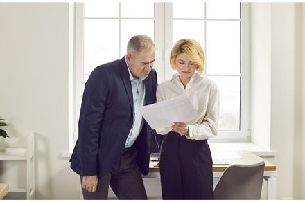 Senior man and young woman standing, a Business Photo by StudioRomantic