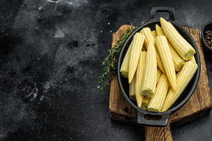 Raw baby corn maize arranged in black skillet top view with thym, a Food & Drink Photo by composter-box@mail.ru
