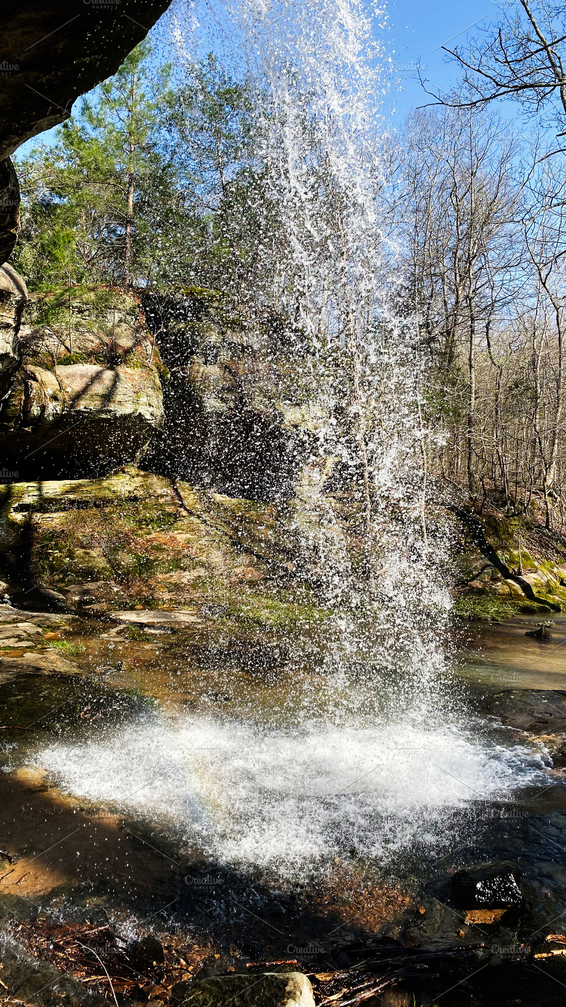 Waterfall in Indiana park with rocky ledge, spray, and clear blue sky, a Photo by AS photostudio