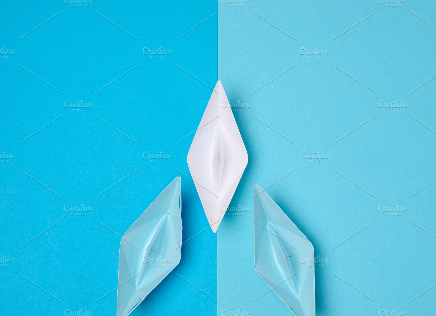 A white origami paper boat symbolizing leadership leads two blue, a Business Photo by ndanko