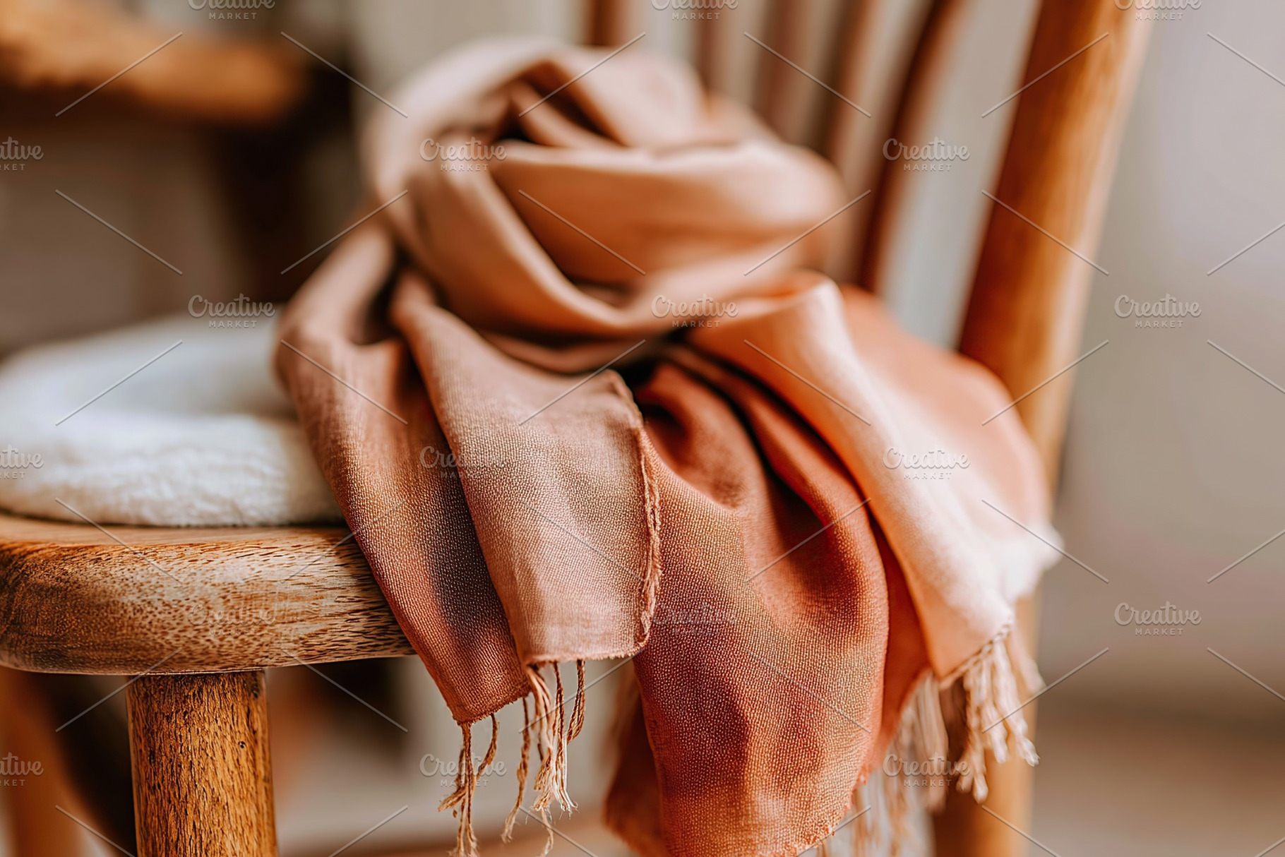 Hand-dyed silk scarf draped elegantly over a wooden chair in a cozy setting at, a Photo by AlyaAnd