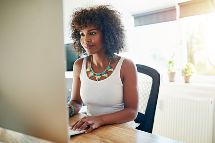 Young African American woman working at a computer, a Business Photo by Stefan & Janni