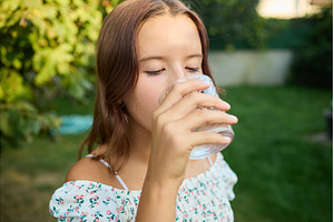 Girl drinks clear water from glass