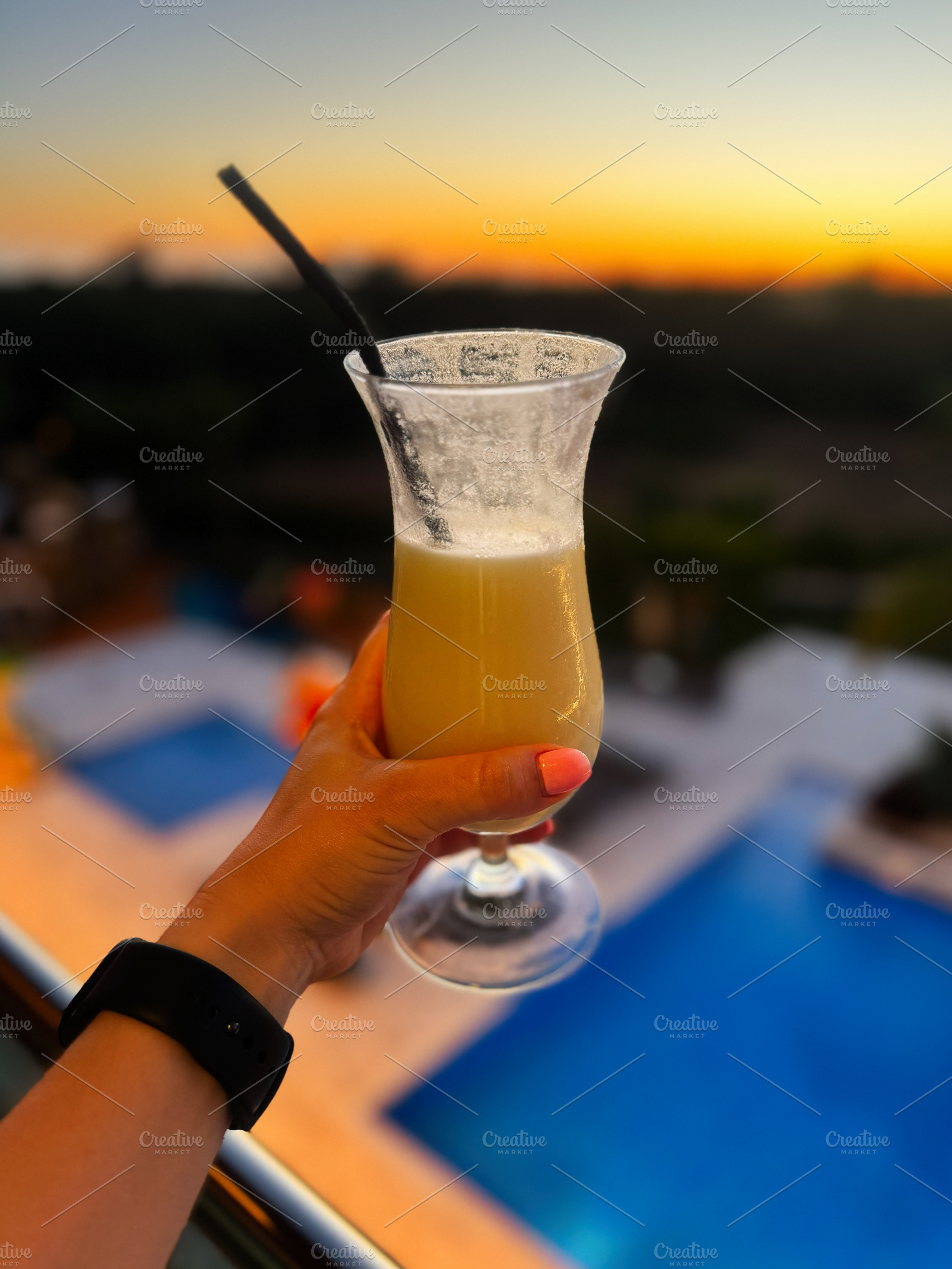 Tropical cocktail held against a sunset near a pool in a serene resort. Algarve, a Photo by AS photostudio