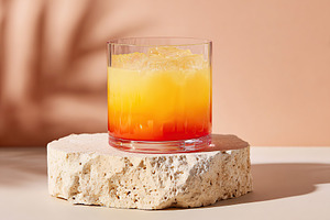 Refreshing layered cocktail served in a glass on a stone coaster, a Food & Drink Photo by AlyaAnd