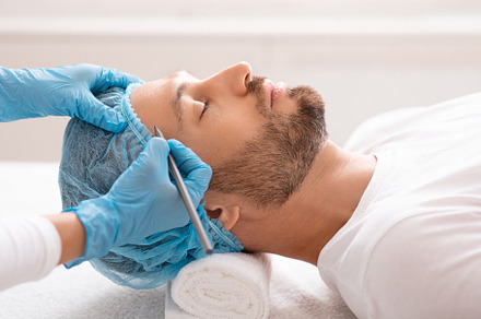 Handsome man getting pencil marks on forehead before surgery, a Photo by Prostock-Studio