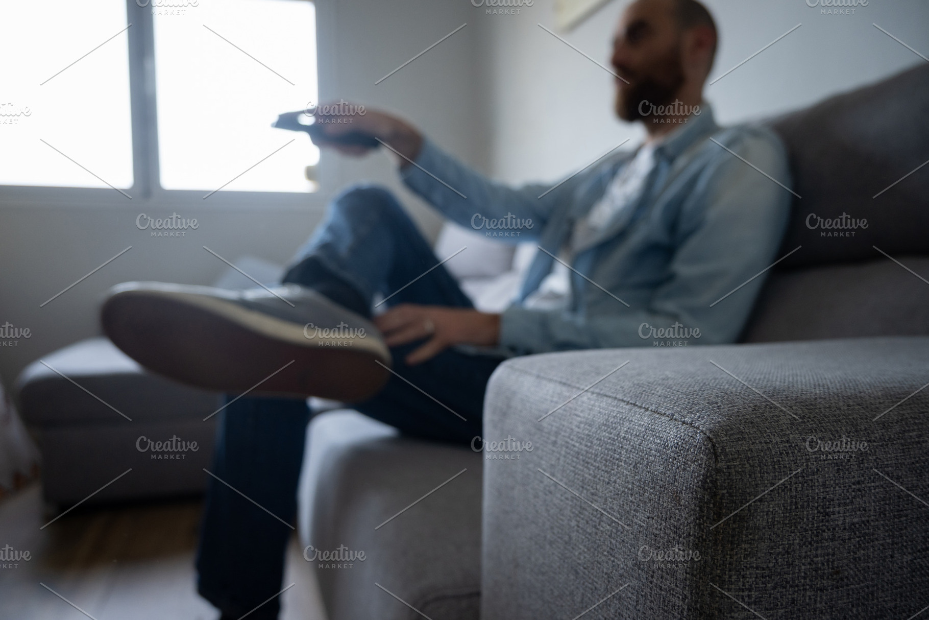 Man relaxing on sofa watching TV at home, blurred lifestyle scene, a Person Photo by etorres69