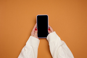 A woman's hands in a white knitted sweater hold a mobile phone w, a Technology Photo by ndanko