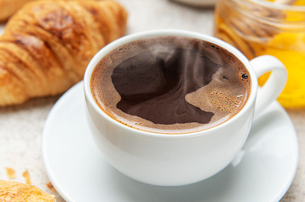 Steaming coffee, fresh croissants, and honey create a tempting b