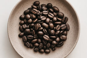 Coffee beans on white plate, a Photo by Virgo Studio