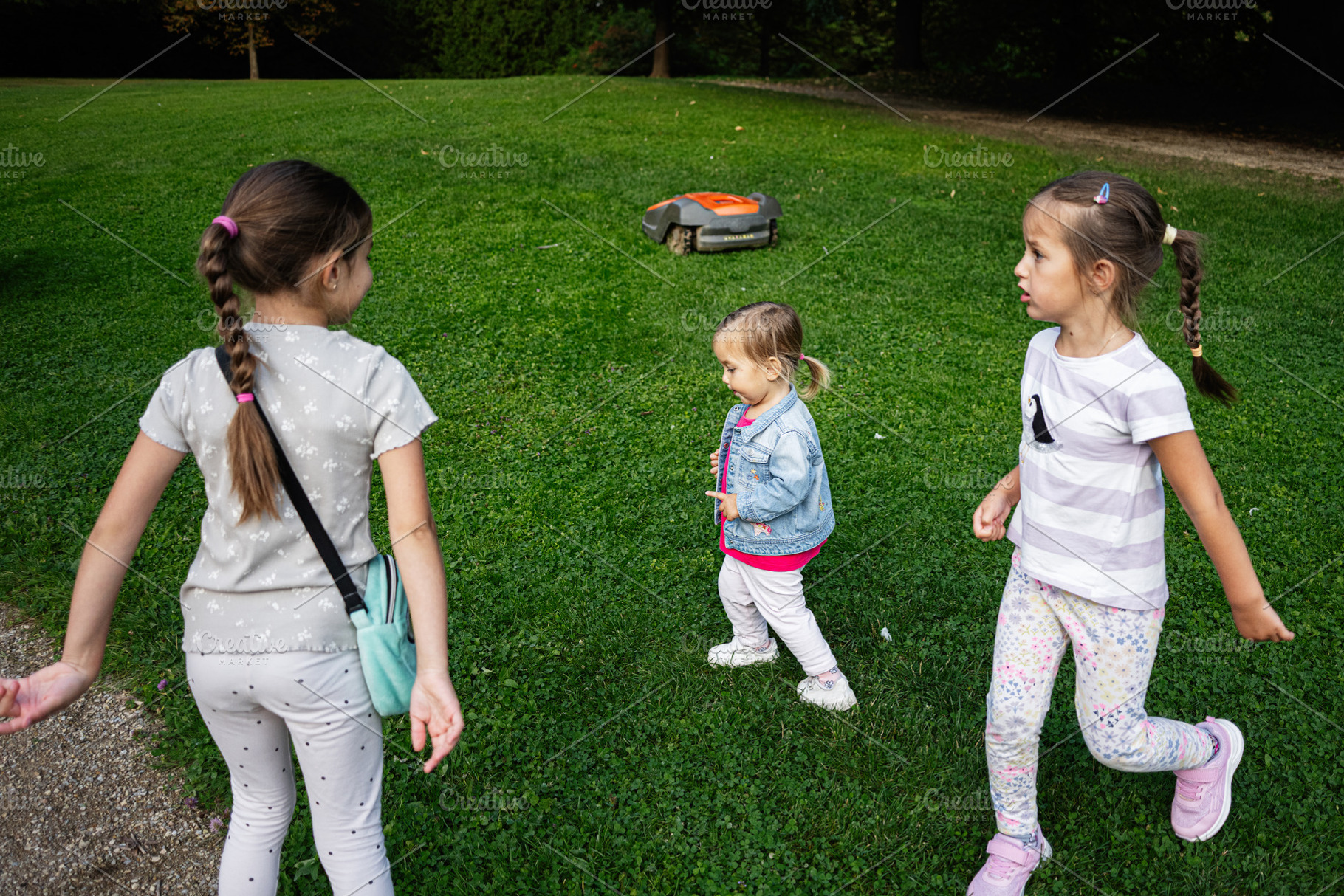 Three children playing outdoors in a park in Lancut, Poland, sunny afternoon, a Photo by AS photostudio