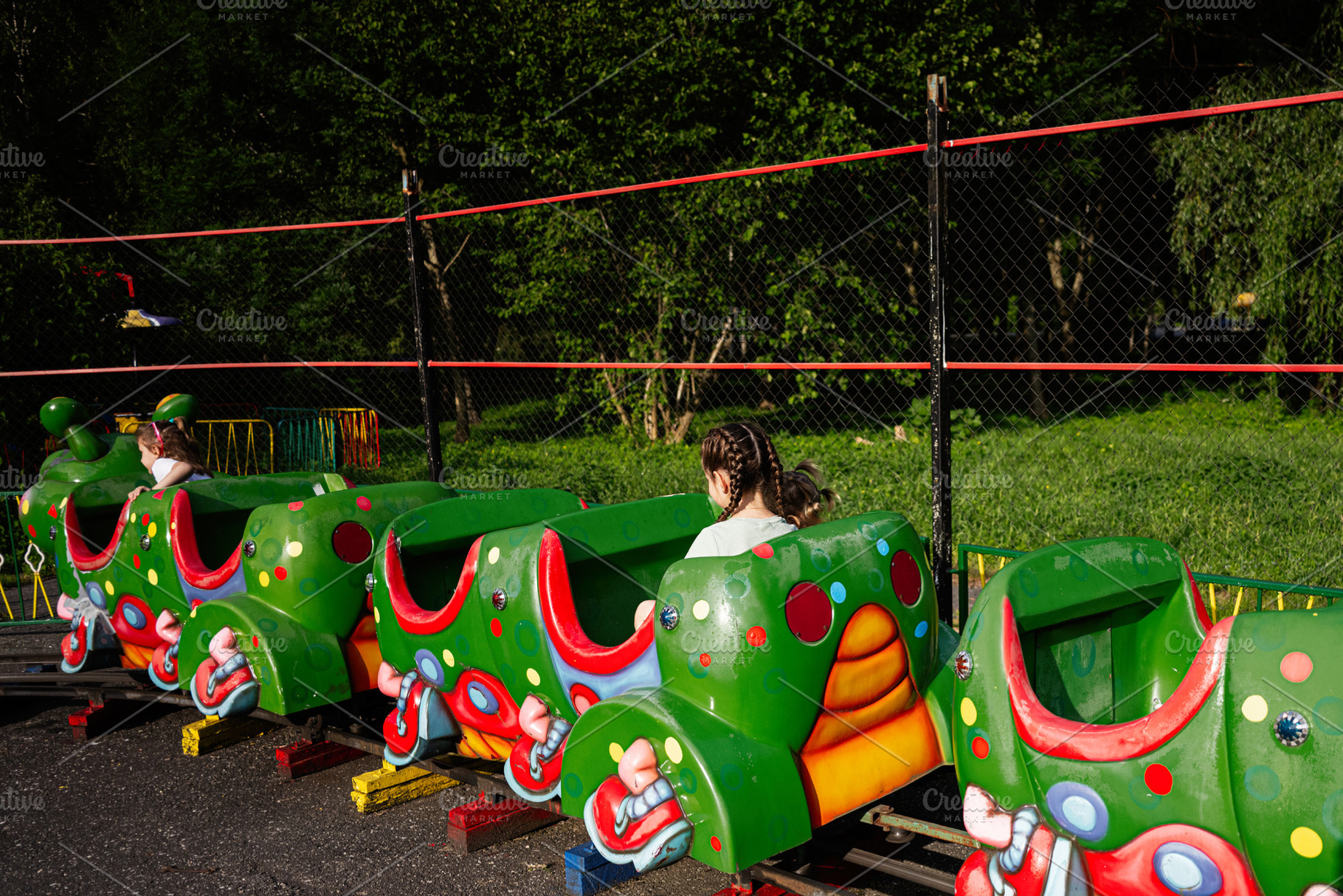 Children enjoying a colorful caterpillar train ride in an outdoor ...