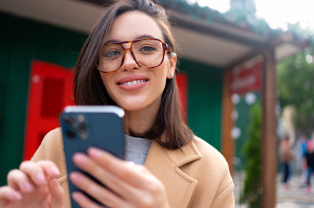 Woman in glasses using mobile phone at day in the city, a Person Photo by andreonegin market