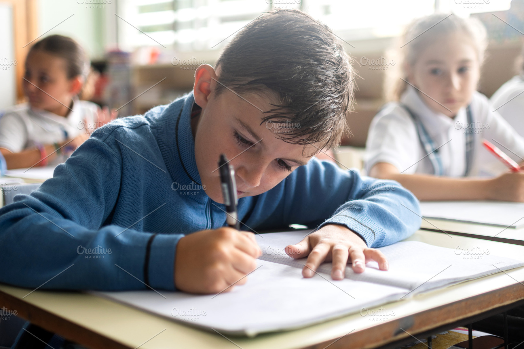 Elementary school boy writing in a notebook during a classroom lesson, a School & Education Photo by etorres69