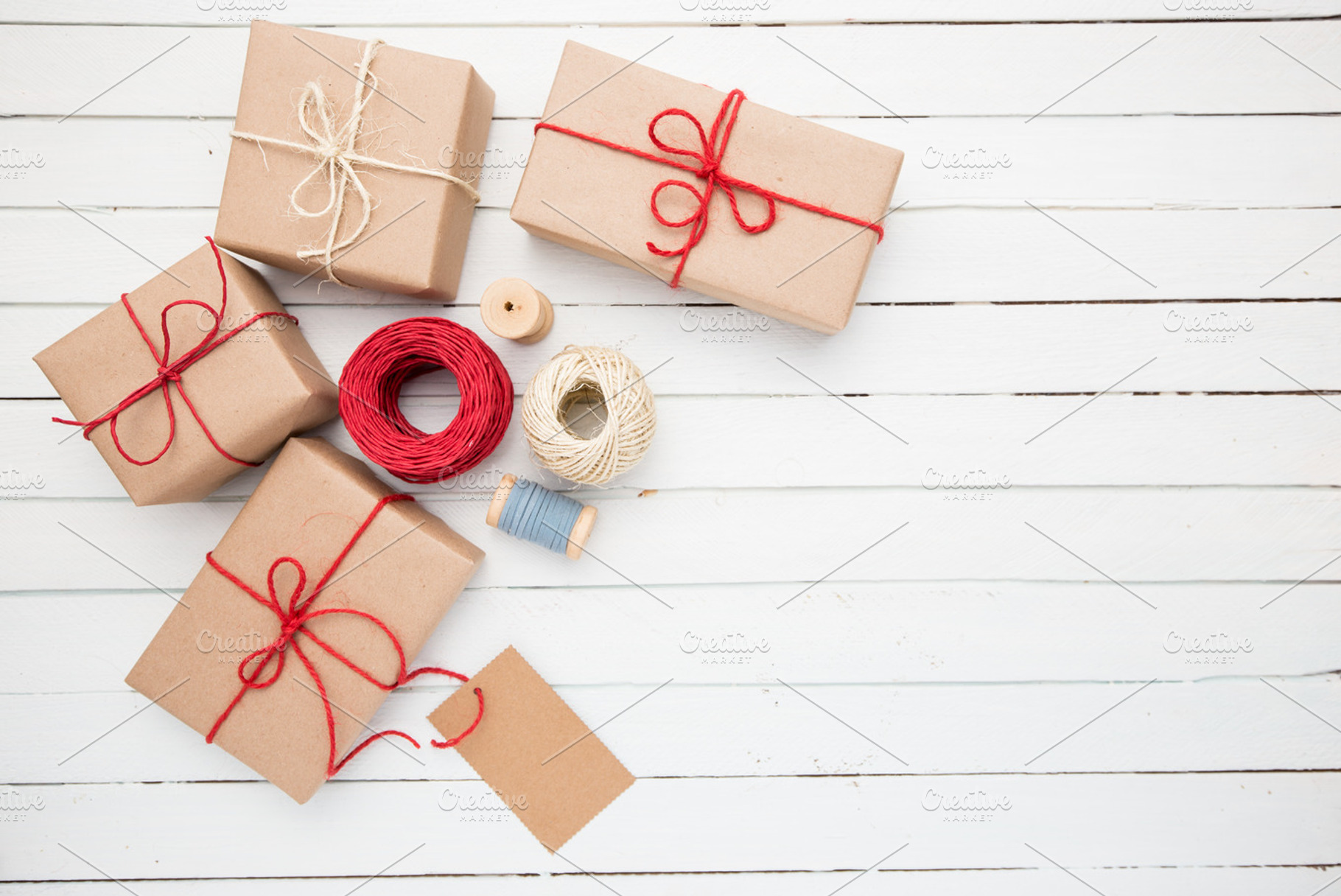 Homemade wrapped rustic brown paper packages on white wooden surface, a Holiday Photo by Maksimkostenko