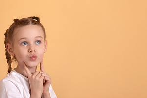 Curious young girl with pigtails in white shirt thinking and loo, a Person Photo by Ales Munt