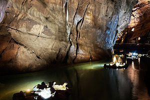 Scenic illuminated cave with water and rock formations in Mira de Aire, Portuga, a Photo by AS photostudio