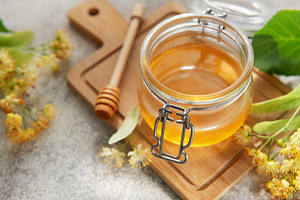 Fresh linden honey jar with blooming flowers, a Food & Drink Photo by Olena Rudo