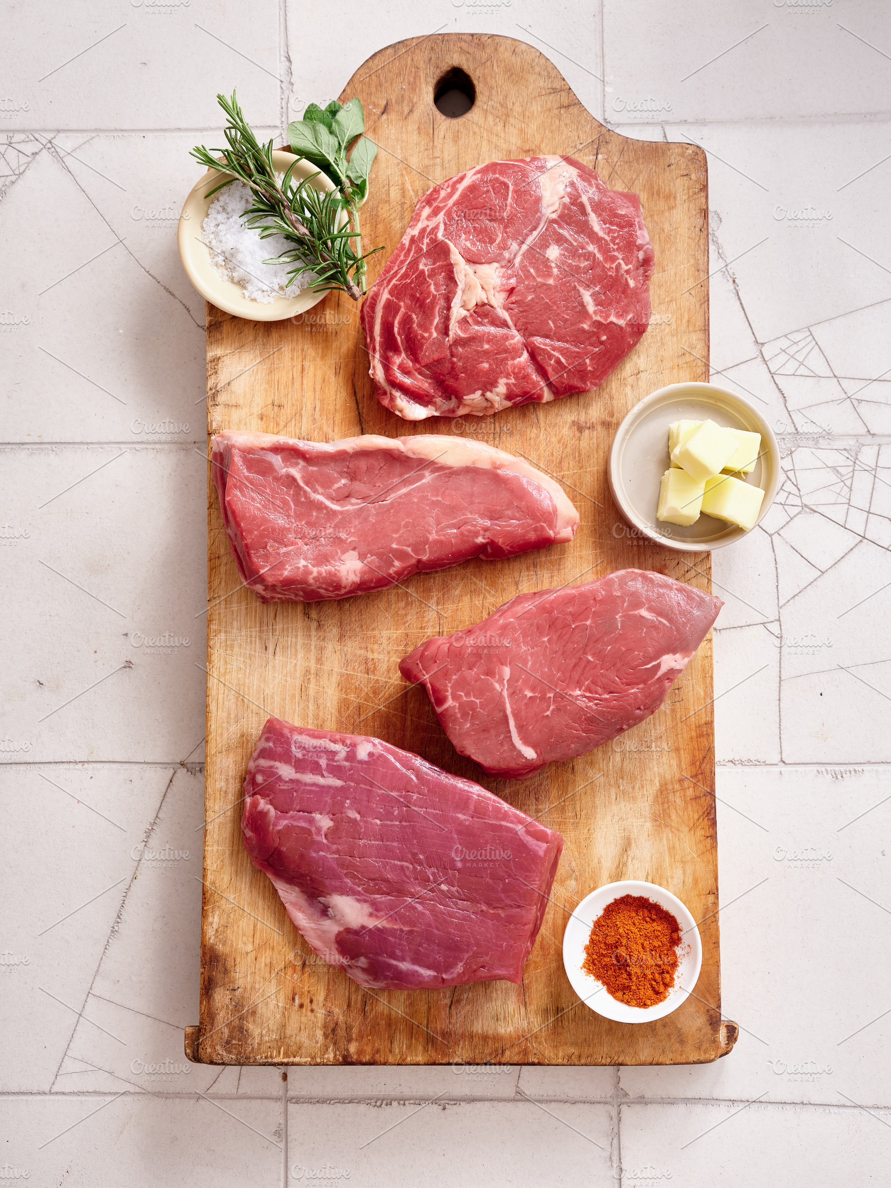 Raw rib-eye, roast beef, flank, and rump steak displayed on a wooden cutting bo, a Food & Drink Photo by Asya Nurullina