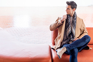 Stylish man seated on sofa in modern urban setting, a Person Photo by RF Images