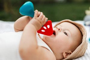 Beautiful happy baby in hat lying on blanket and playing with te, a Person Photo by Sonjachni
