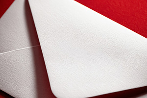 White textured envelope on a vibrant red background, suggesting, a Photo by Studio ANNA