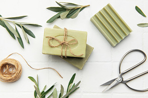 Natural olive soap bars with twine and scissors on white tile ba, a Health & Medical Photo by Olena Rudo