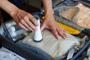 a man flattens clothes in a suitcase with a pump, a Photo by Nito