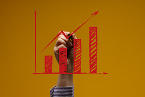 A person's hand draws a red bar graph with an upward arrow on a, a Business Photo by ndanko