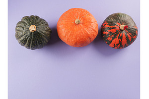 Three colorful pumpkins on purple
