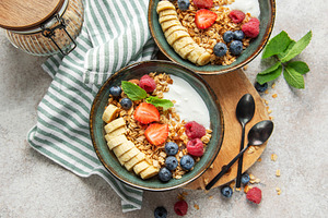 Healthy breakfast bowls with yogurt, granola, banana, and berrie, a Food & Drink Photo by Olena Rudo