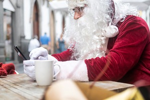 Santa Claus using smartphone during coffee break at cafe, a Holiday Photo by etorres69