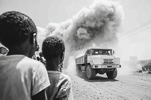 Dust storm rises from truck as children observe in urban setting during daytime, a Transportation Photo by AlyaAnd