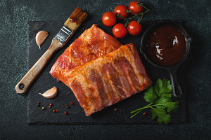 Ready for BBQ raw pork spare ribs with barbecue sauce. Black background. Top vi, a Food & Drink Photo by Budarinphoto