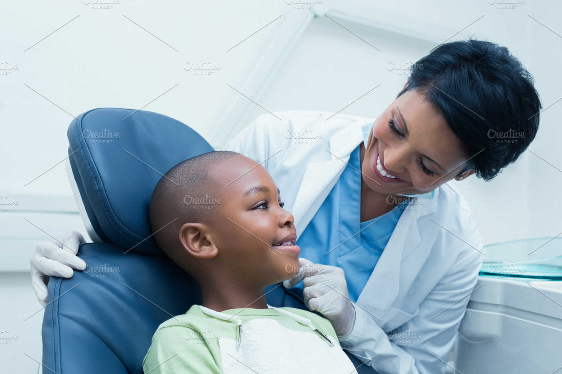 Female dentist examining boys teeth, a Photo by wavebreak