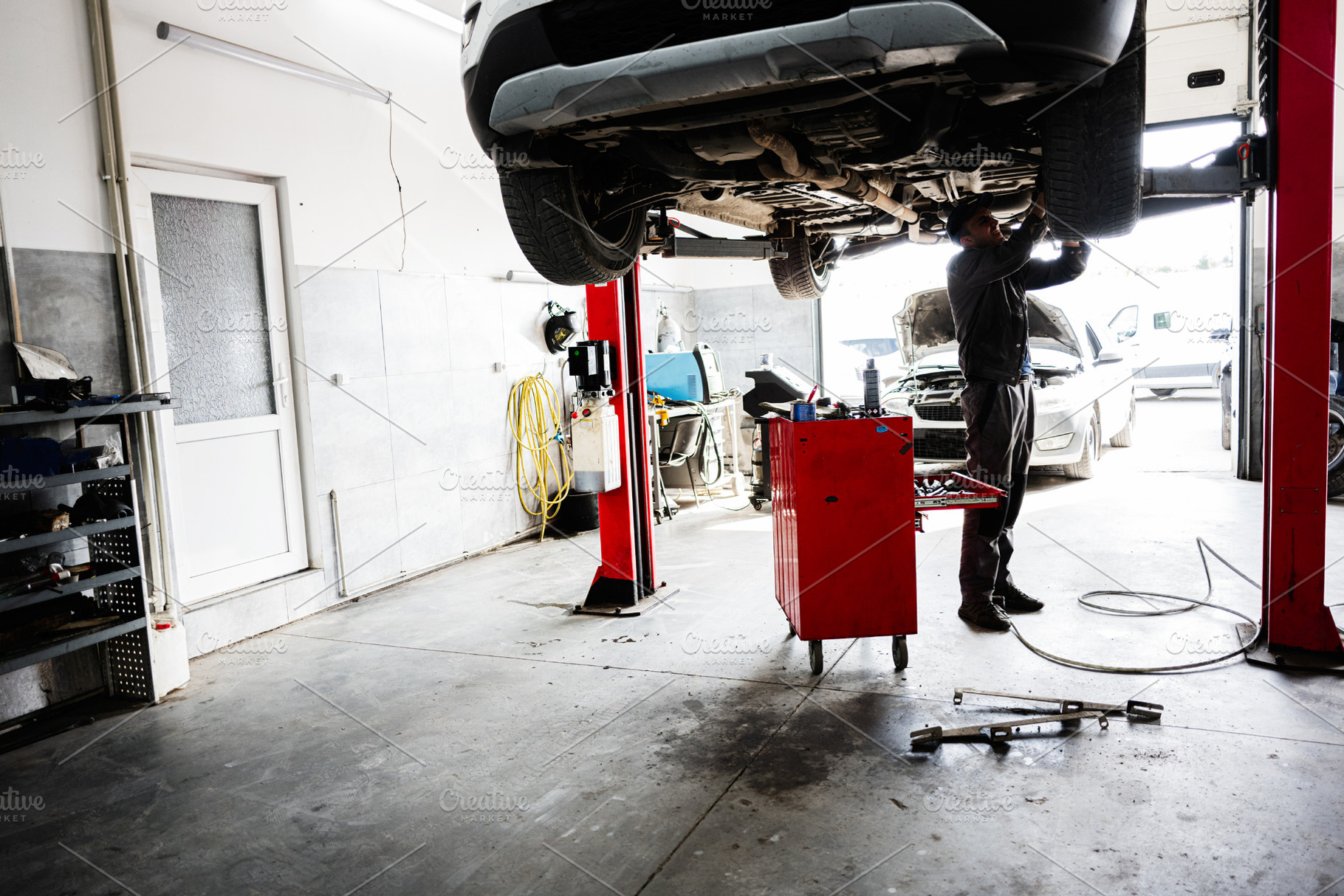 Mechanic working under car in a vehicle garage workshop maintenance environment, a Transportation Photo by AS photostudio