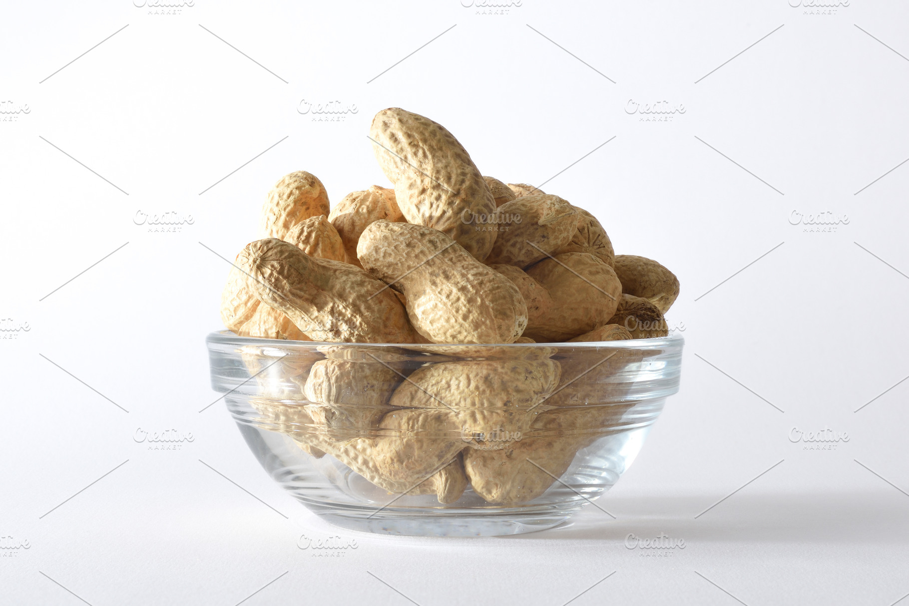 Detail of glass bowl with peanuts in shell isolated background, a Food & Drink Photo by Davizro's Market