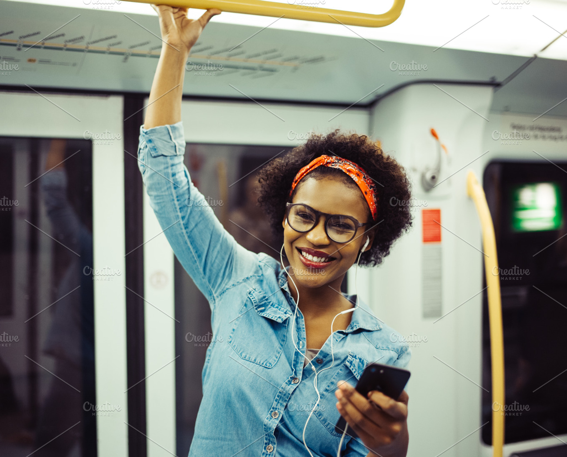 Smiling young african woman listening to music on the subway featuring 20s, a Person Photo by Stefan & Janni