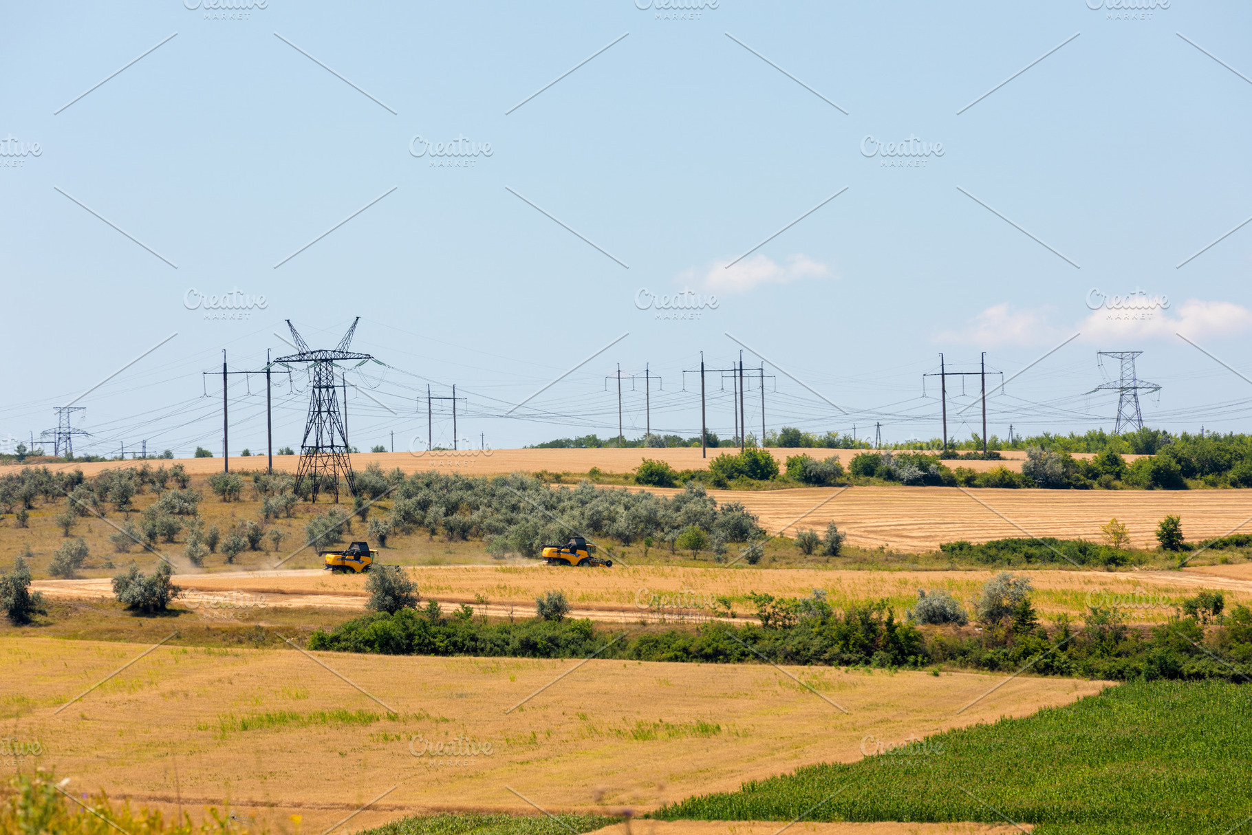 Two yellow combine harvesters working in a golden field under cl, an Industrial Photo by Ales Munt