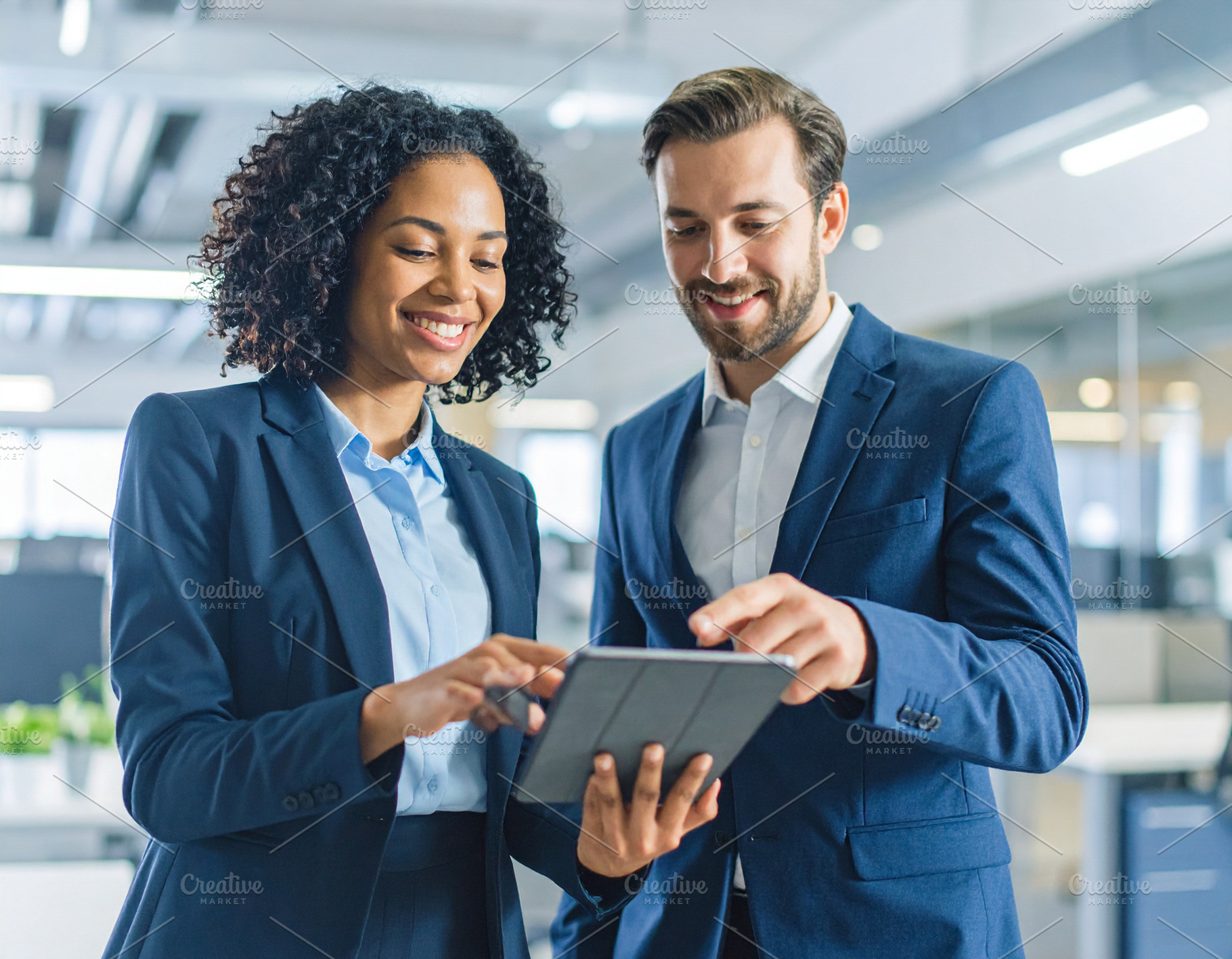 Coworkers pointing at a tablet and smiling, symbolizing knowledg, a School & Education Photo by DanFLCreativo