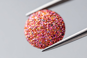 Glittery round object held with tweezers, an Abstract Photo by AlyaAnd