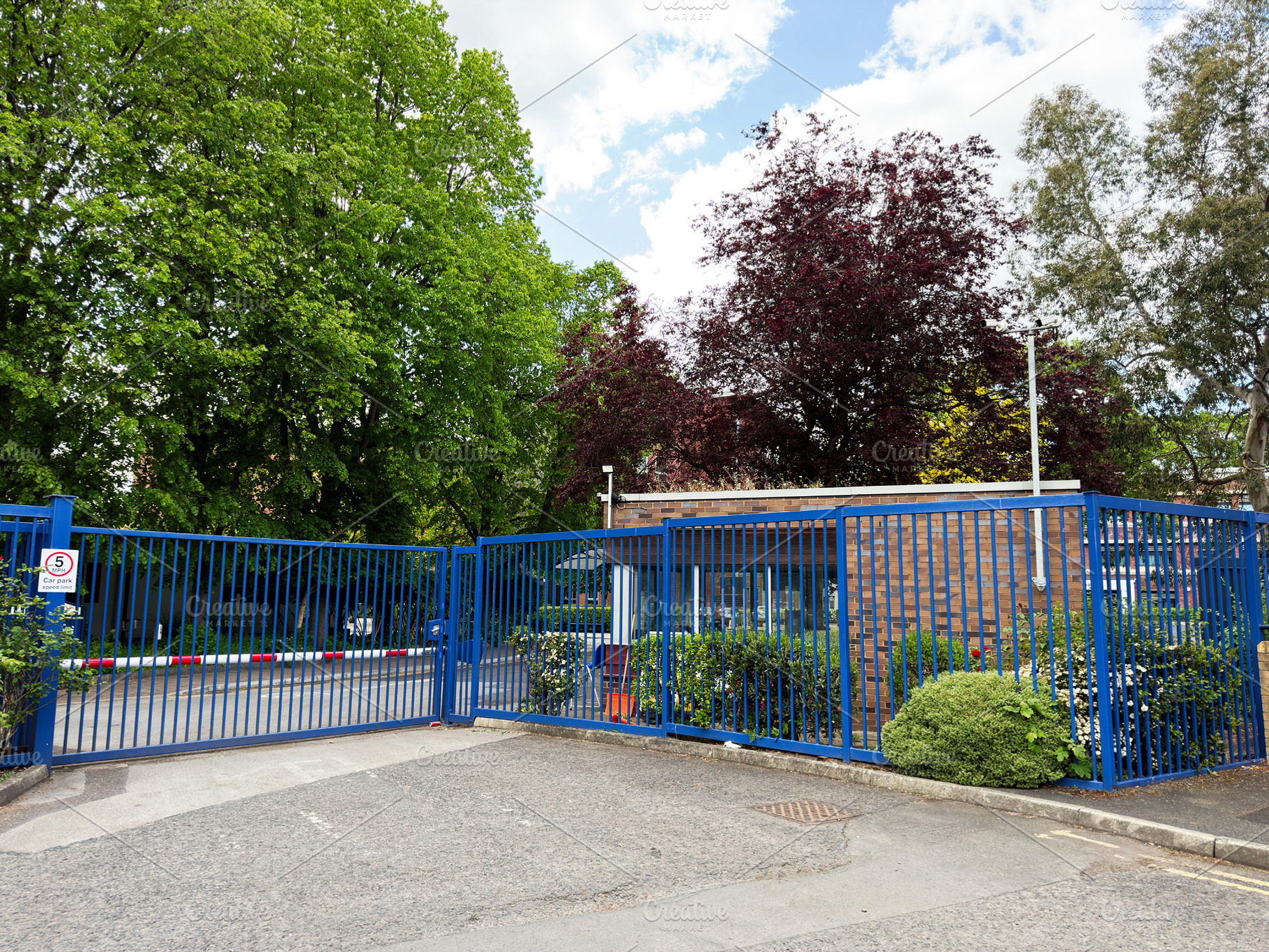 Secure gated entrance with blue metal fence and guardhouse at a, a Photo by AS photostudio