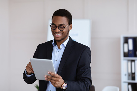 Positive black guy entrepreneur using digital tablet in office, a Photo by Prostock-Studio