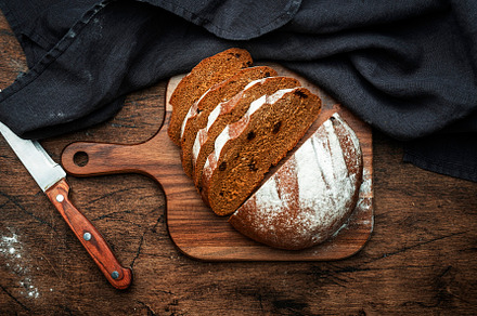 Sourdough rye bread with raisins, pieces on wooden cutting board, a Food & Drink Photo by 5PH