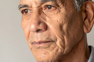 Thoughtful senior man gazing sideways with gentle expression, a Person Photo by GoodGoods