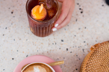 A hand with a cold drink and coffee