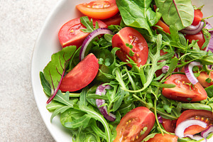 Fresh vegetable salad with arugula, tomatoes, and red onion, a Photo by Olena Rudo